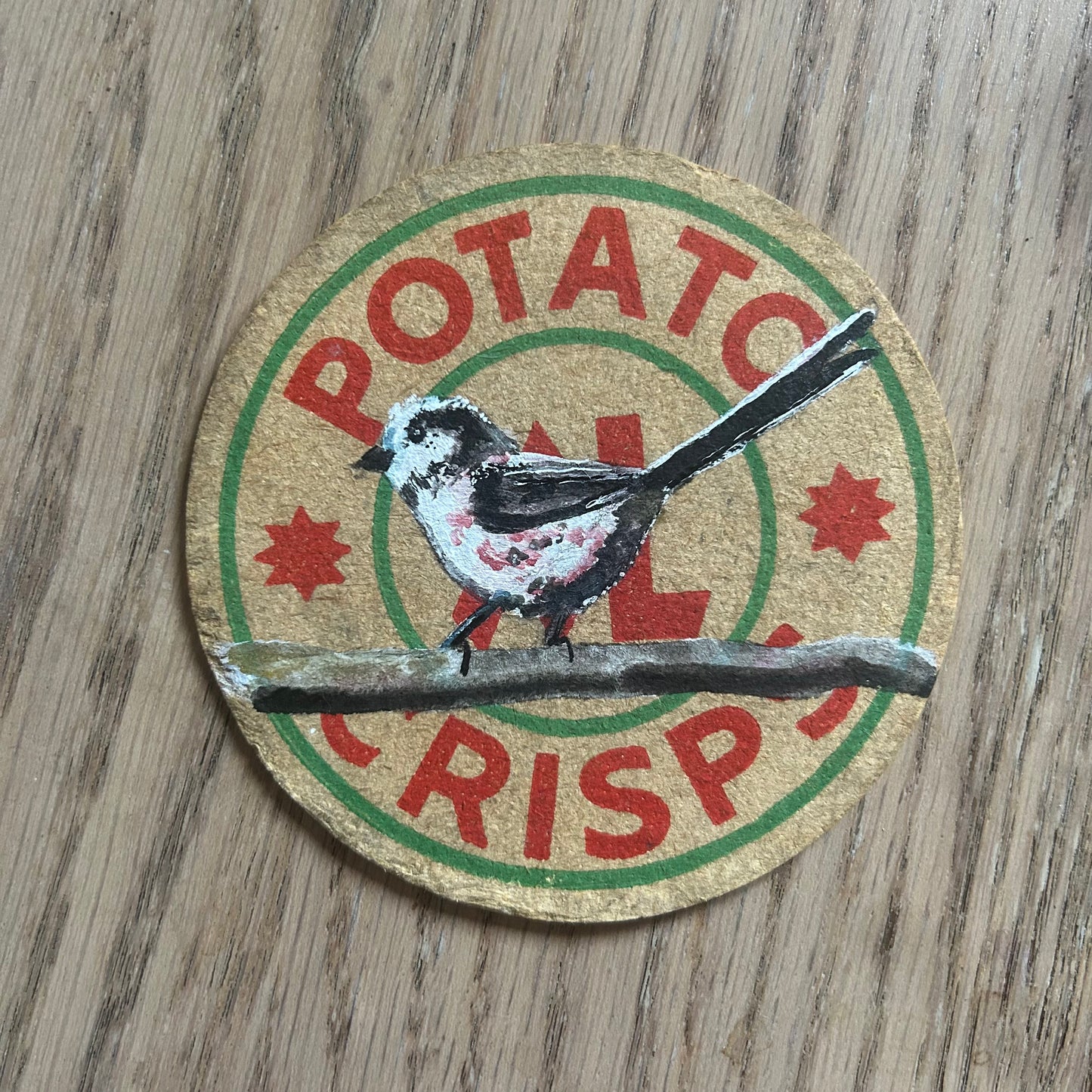 A Longtailed Tit painted onto an XL potato crisps drinks mat from the 1950s. Beermat painting. Watercolour.