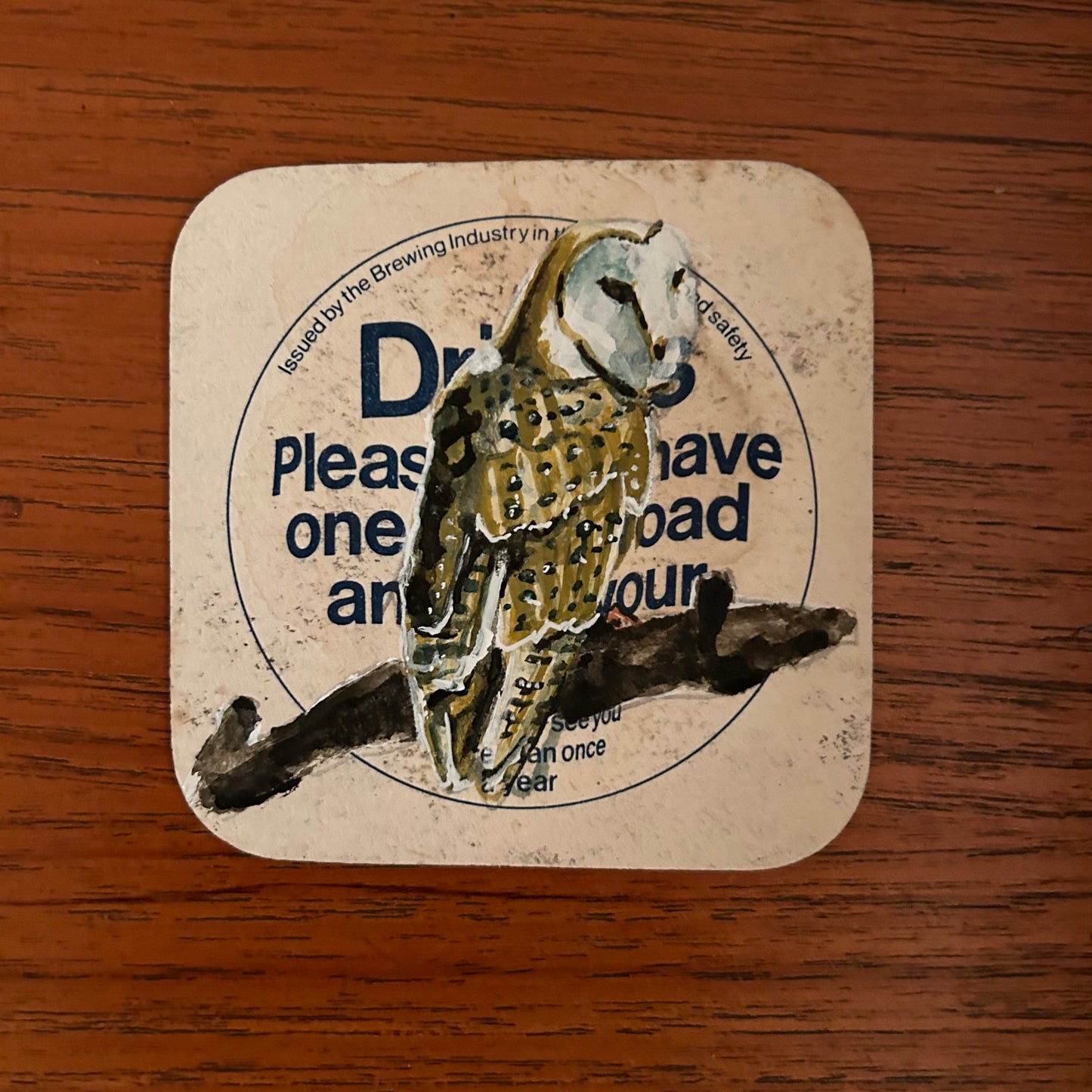 A Barn Owl painted onto a drink/drive Courage beer mat from the 1970s. Beermat painting. Watercolour.