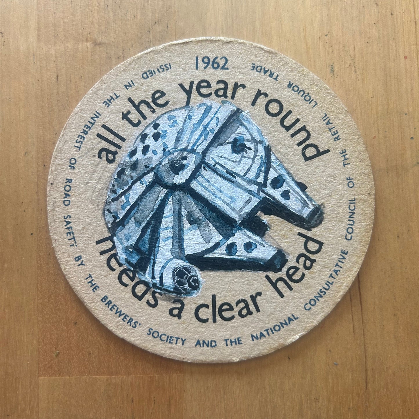 The Millenium Falcon painted on a ‘Driving All The Year Round Needs a Clearer Head’ Beermat from 1962. Beermat painting. Watercolour.