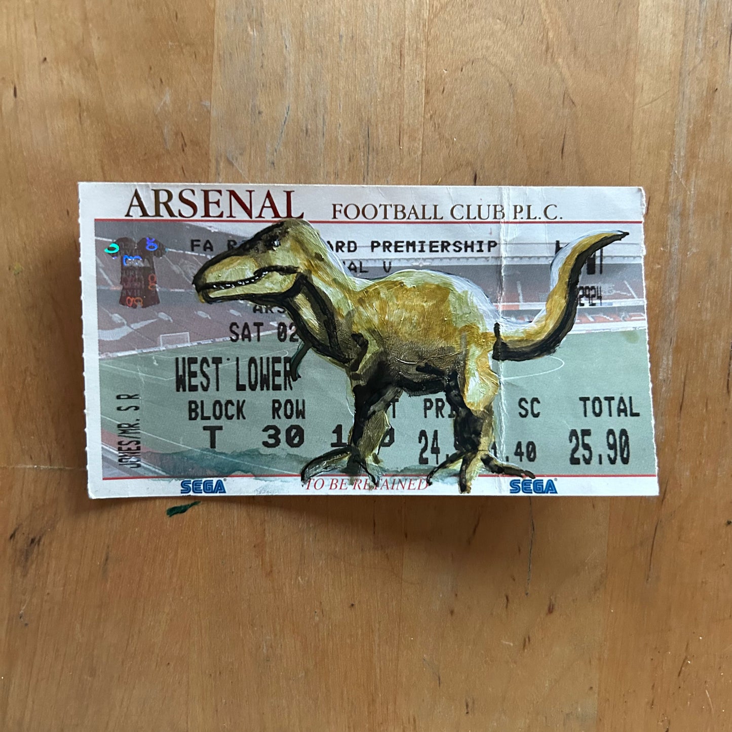 A dinosaur painted onto a football ticket Match ticket - Arsenal v Southampton 02/02/2002 Premiership- Watercolour. Ticket has a crease in it.