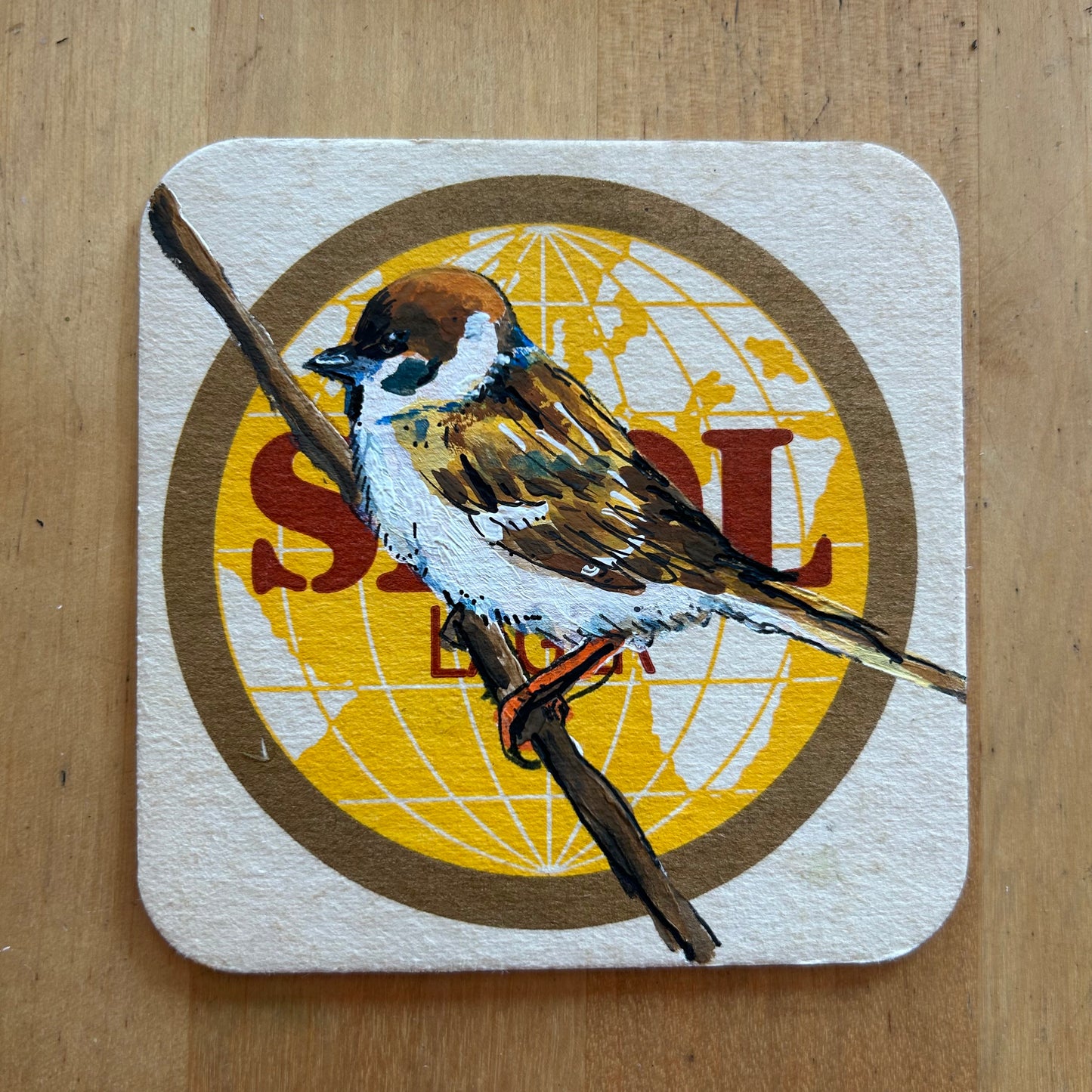 A Sparrow painted onto a Skol beermat. Beermat painting. Watercolour.