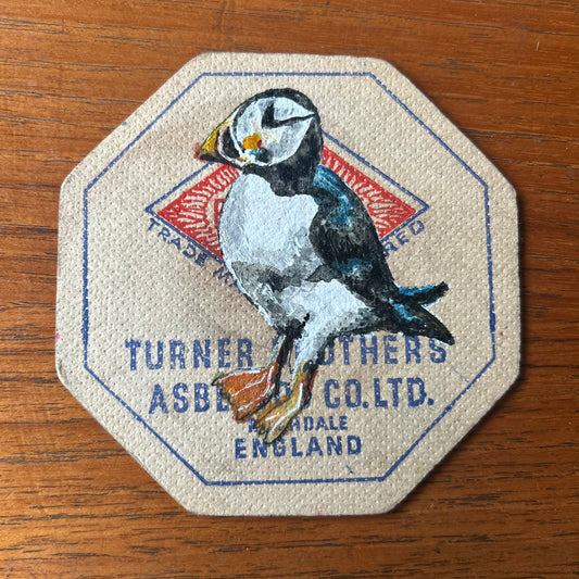 A puffin painted onto a 1957 Turner brothers Asbestos Co. Beer mat from Rochdale. Beer mat painting. watercolour and acrylic on card.
