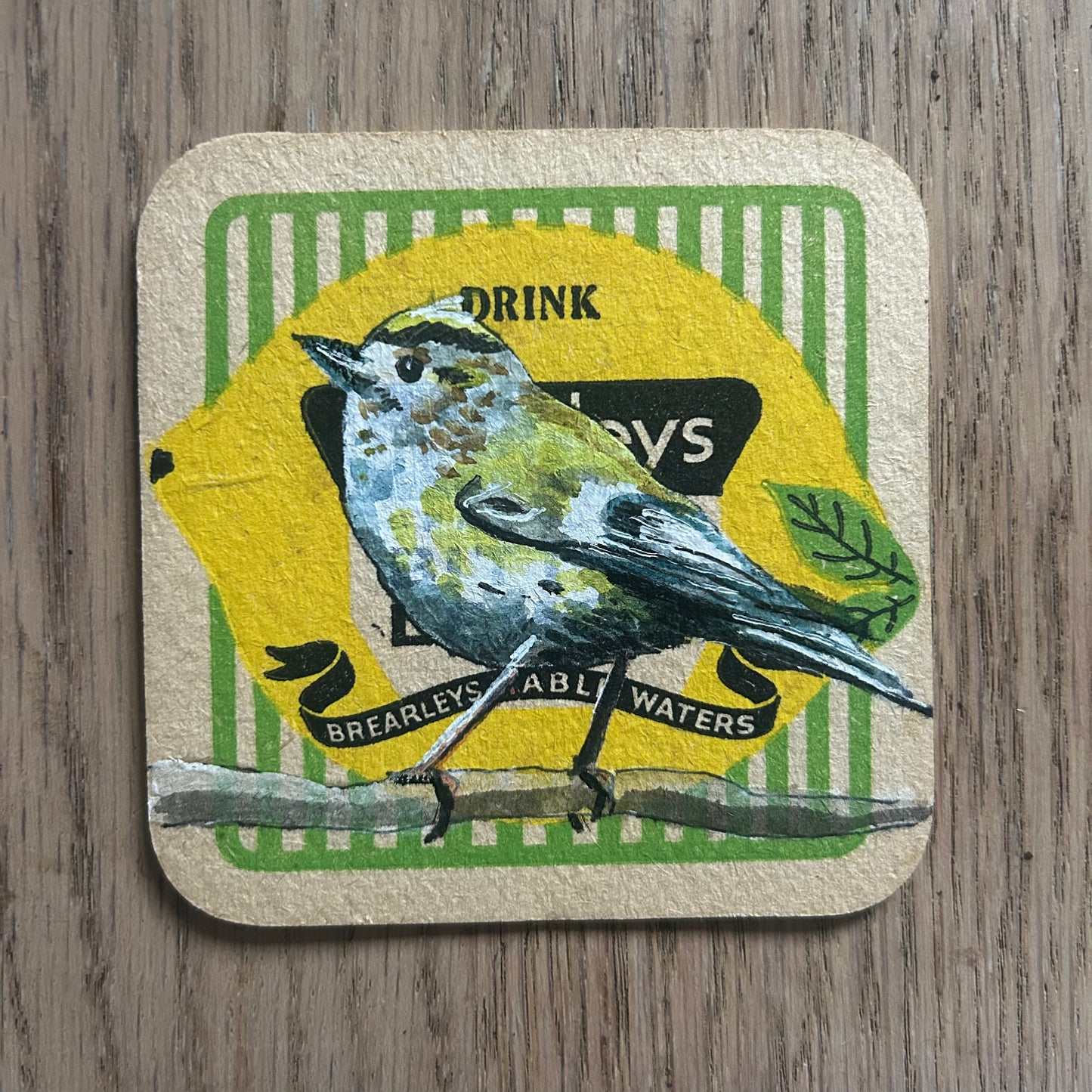 A Goldcrest painted onto a Brearley’s soft drinks mat from the 1950s. Beermat painting. Watercolour.