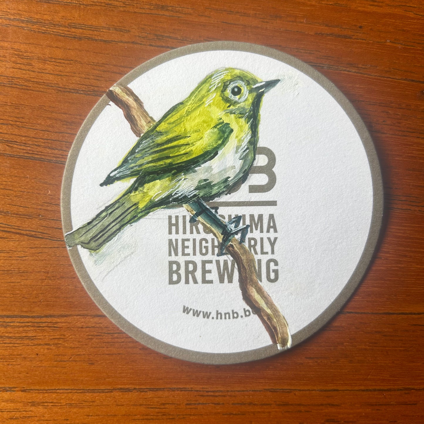 A Japanese White Eye painted on a beer mat from Hiroshima Neighbourly Brewing. Beermat painting. Watercolour.