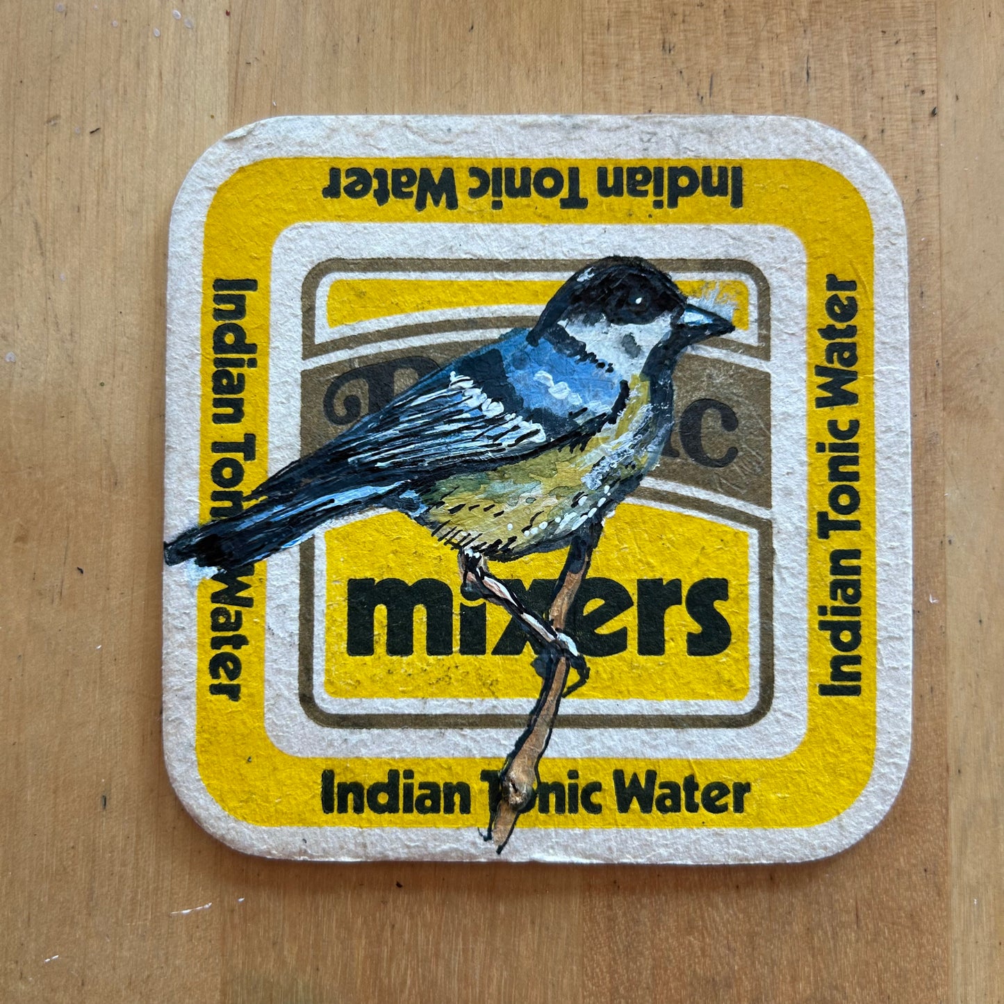 A Great Tit painted onto a Britvic mixers drinks mat. Beermat painting. Watercolour.