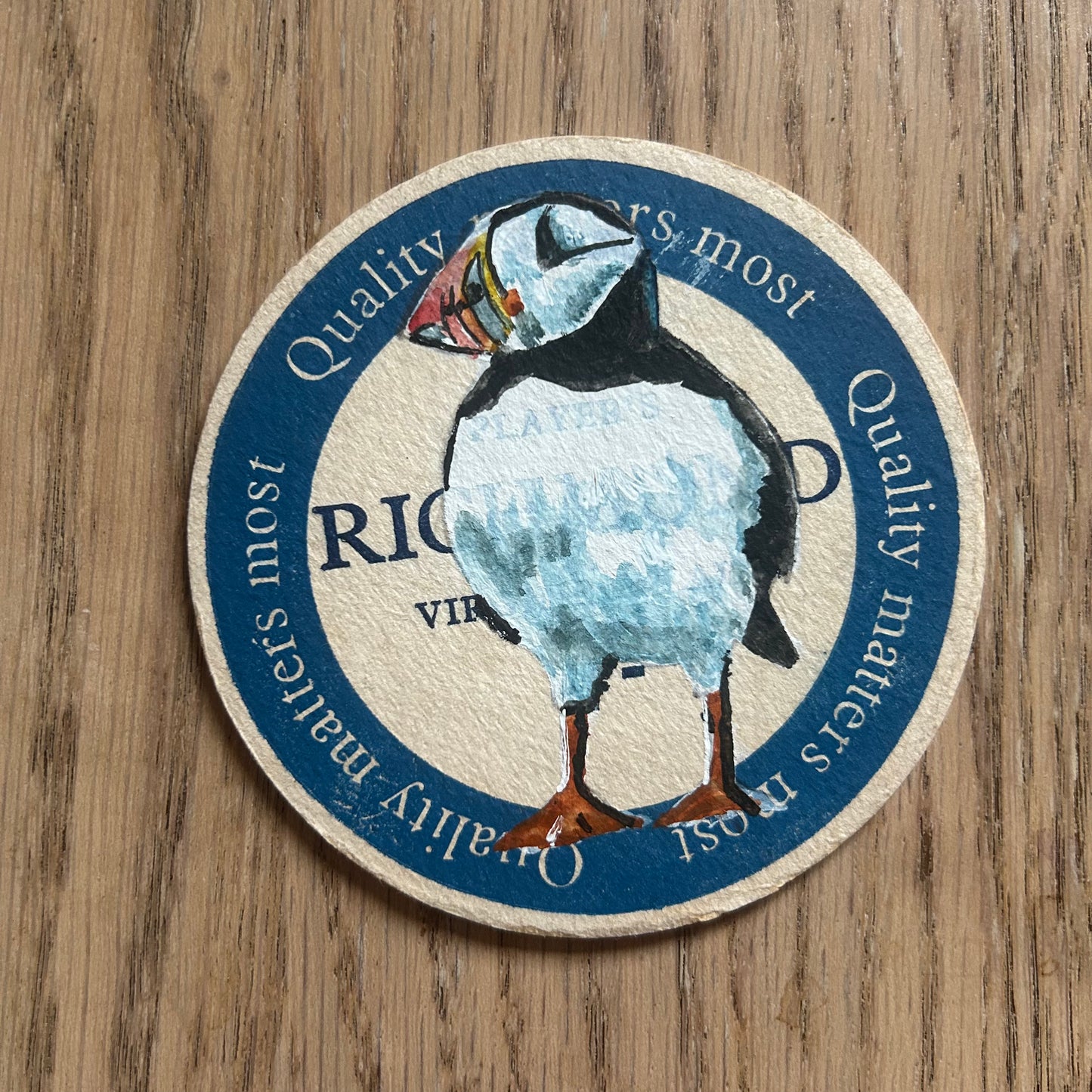 A Puffin painted onto a Players Richmond cigarettes drinks mat from the 1950s. Beermat painting. Watercolour.