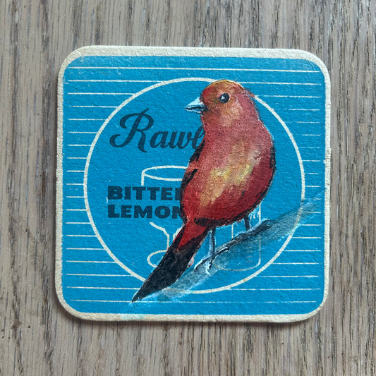 A Scarlet Tanager Songbird painted onto a Rawlings soft drinks mat from the 1950s. Beermat painting. Watercolour.